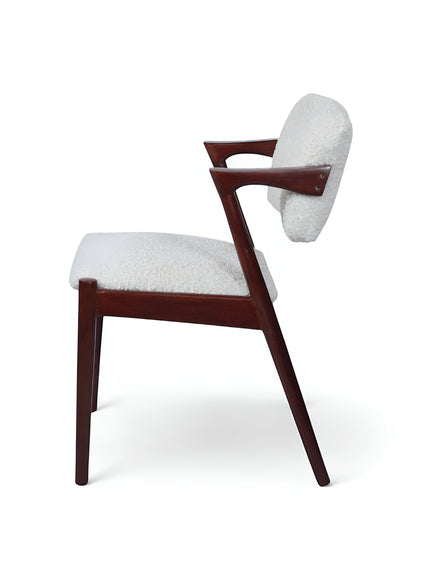 Front angled view of the Vaya Home Angolo dining chair with white boucle upholstery, angled wood arms, and a dark wood frame.