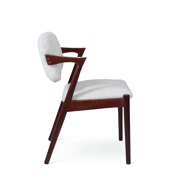 Side view of the Vaya Home Angolo dining chair with white boucle upholstery, angled wood arms, and a dark wood frame.