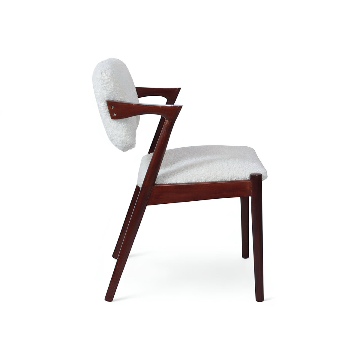 Side view of the Vaya Home Angolo dining chair with white boucle upholstery, angled wood arms, and a dark wood frame.
