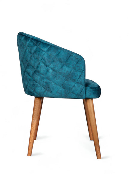 Side view of the Vaya Home Antigo dining chair with blue velvet upholstery, quilted outer back, and tapered wood legs.