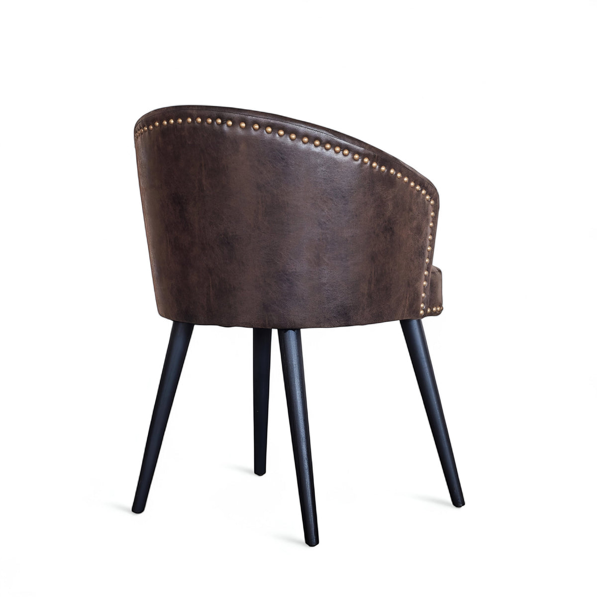 Rear angled view of the Vaya Home Antigo dining chair with dark brown leather upholstery, nailhead trim, barrel back, and black tapered legs.
