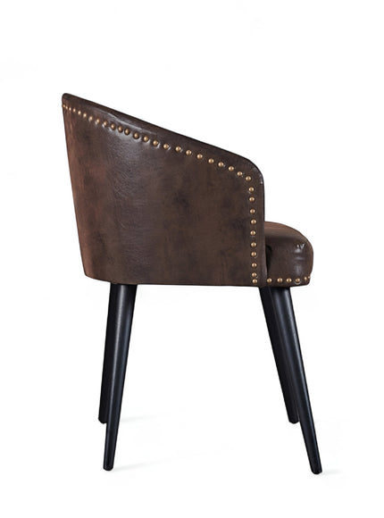 Side view of the Vaya Home Antigo dining chair featuring dark brown leather upholstery, curved barrel back, and black tapered legs.