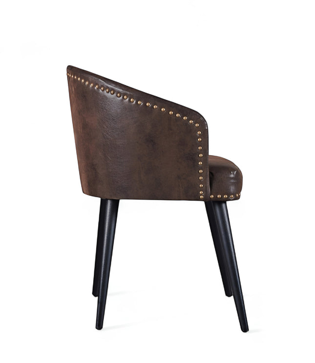 Side view of the Vaya Home Antigo dining chair featuring dark brown leather upholstery, curved barrel back, and black tapered legs.