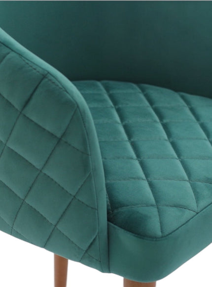 Close-up of the Vaya Home Antigo dining chair showing green velvet upholstery and diamond-quilted seat and back detail.