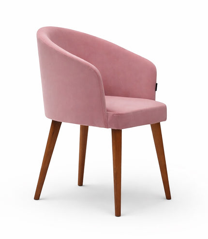 Front angled view of the Vaya Home Antigo dining chair with pink velvet upholstery, curved barrel back, and tapered wood legs.