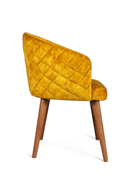 Side view of the Vaya Home Antigo dining chair with yellow velvet upholstery, quilted outer back, and tapered wood legs.
