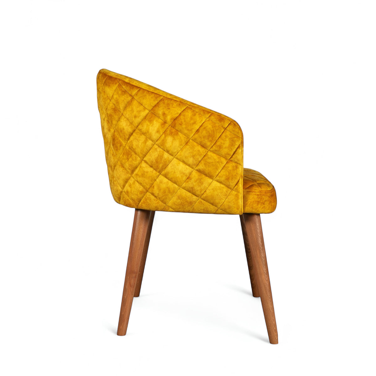 Side view of the Vaya Home Antigo dining chair with yellow velvet upholstery, quilted outer back, and tapered wood legs.