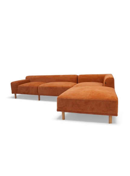 Angled view of the Vaya Home Arancio modular sofa featuring rust orange upholstery, slim legs, and modular seating sections.