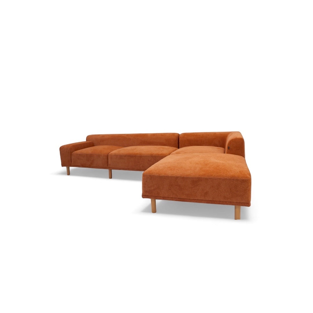 Angled view of the Vaya Home Arancio modular sofa featuring rust orange upholstery, slim legs, and modular seating sections.