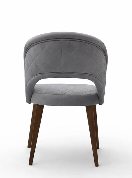 Back view of the Vaya Home Argent dining chair with quilted grey upholstery, open-back detail, and tapered wood legs.