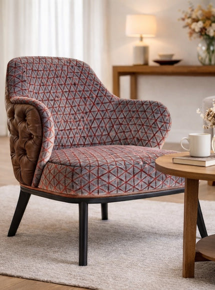 Vaya Home Array accent chair with geometric patterned upholstery, tufted brown leather outer back, and black legs, styled in a modern living room.