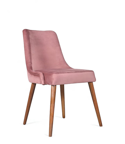 Front angled view of the Vaya Home Arrossire dining chair with pink velvet upholstery, cushioned seat, and tapered wood legs.