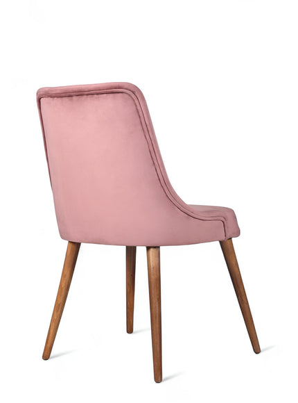 Rear angled view of the Vaya Home Arrossire dining chair featuring pink velvet upholstery, a softly curved backrest, and tapered wood legs.