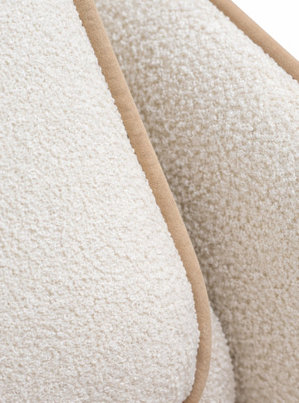 Close-up of the Vaya Home Aureo chair bed showing cream boucle upholstery and piped edge detailing.