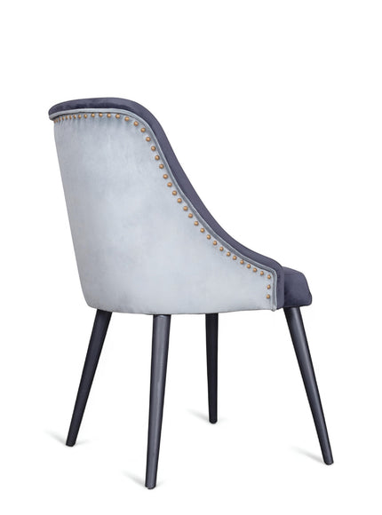 Side view of the Vaya Home Azzurro dining chair with dark blue upholstery, contrast piping, and tapered dark legs.