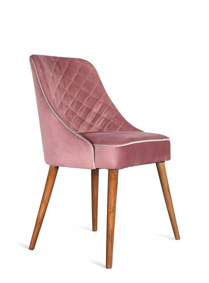 Front angled view of the Vaya Home Azzurro dining chair with pink upholstery, quilted back detail, and tapered wood legs.
