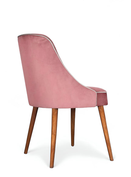Side view of the Vaya Home Azzurro dining chair with pink upholstery and tapered wood legs.