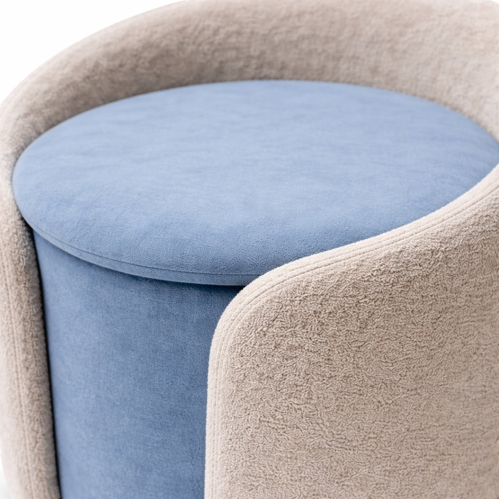 Close-up of the Vaya Home Barrel storage ottoman featuring a blue cushioned seat and light cream outer upholstery.