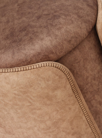 Close-up of the Vaya Home Barrel storage ottoman showing brown upholstered texture and stitched edge detailing.