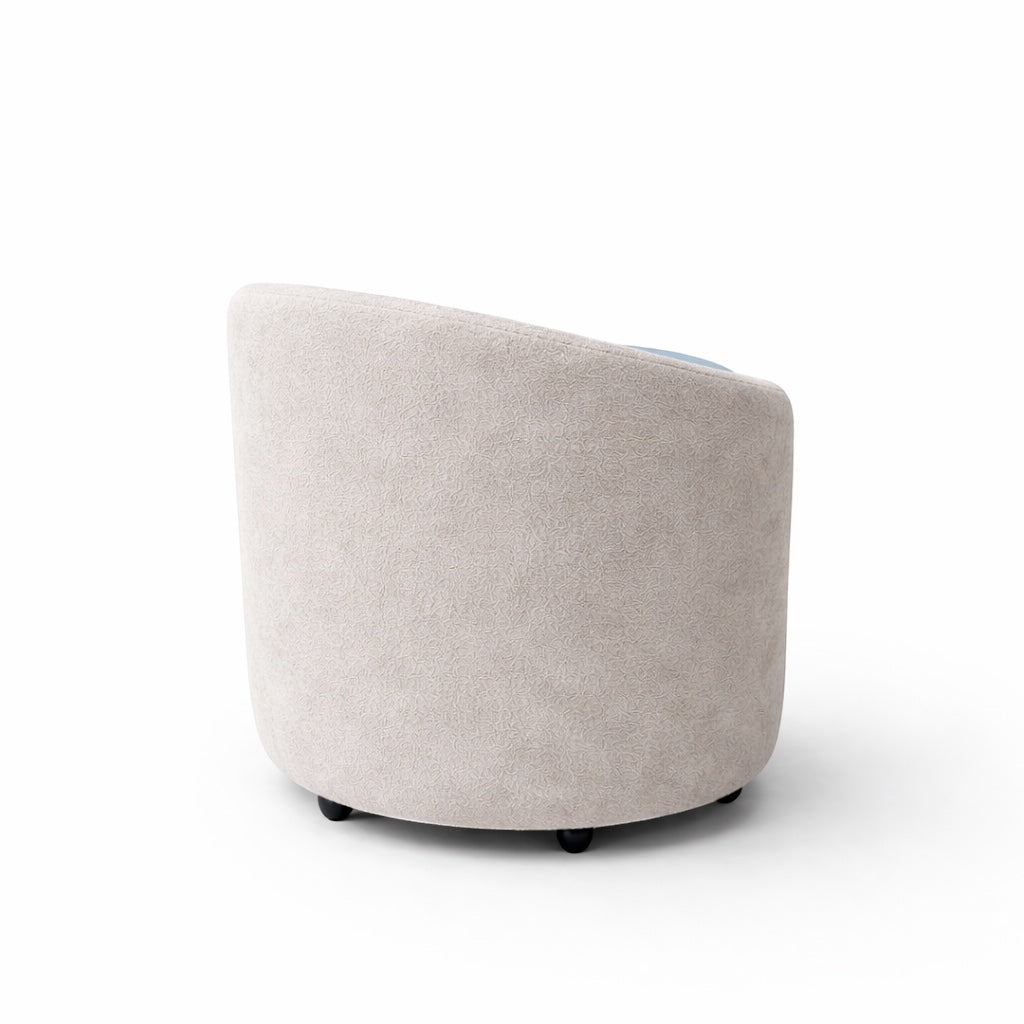 Back view of the Vaya Home Barrel round storage ottoman in light cream upholstery.