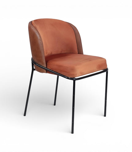 Front angled view of the Vaya Home Batata dining chair with warm brown upholstery, curved backrest, and slim black metal legs.