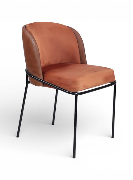 Front angled view of the Vaya Home Batata dining chair with warm brown upholstery, curved backrest, and slim black metal legs.