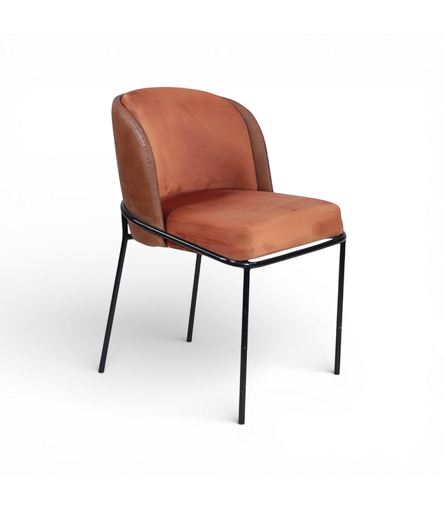 Front angled view of the Vaya Home Batata dining chair with warm brown upholstery, curved backrest, and slim black metal legs.