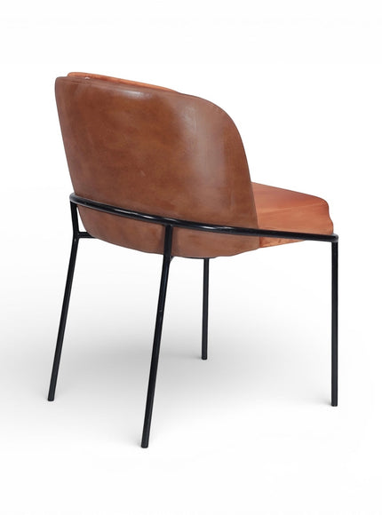 Rear angled view of the Vaya Home Batata dining chair with brown upholstery and slim black metal legs.