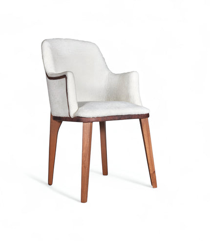 Front angled view of the Vaya Home Cadena dining chair with white boucle upholstery, sculpted arms, and tapered wood legs.