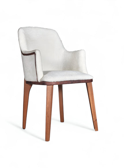 Front angled view of the Vaya Home Cadena dining chair with white boucle upholstery, sculpted arms, and tapered wood legs.