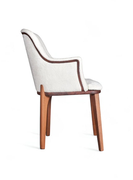 Side view of the Vaya Home Cadena dining chair with white boucle upholstery, curved arm detail, and tapered wood legs.