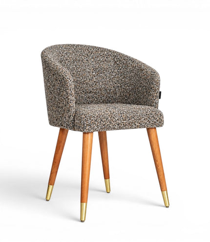 Front angled view of the Vaya Home Cambria accent chair with multitone textured upholstery, a rounded barrel back, and tapered wood legs with gold caps.
