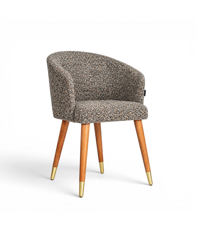 Front angled view of the Vaya Home Cambria accent chair with multitone textured upholstery, a rounded barrel back, and tapered wood legs with gold caps.