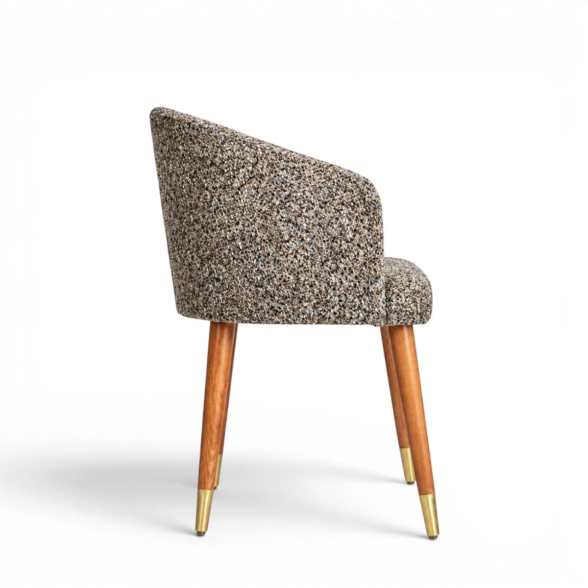 Side view of the Vaya Home Cambria accent chair featuring multitone textured upholstery, a curved backrest, and tapered wood legs with gold caps.