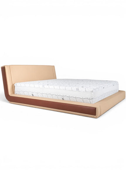 Front angled view of the Vaya Home Camelia bed with beige upholstery, a low platform frame, and warm brown side detailing.