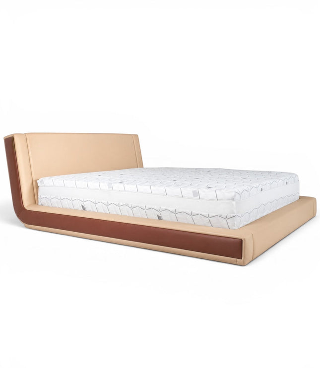Front angled view of the Vaya Home Camelia bed with beige upholstery, a low platform frame, and warm brown side detailing.