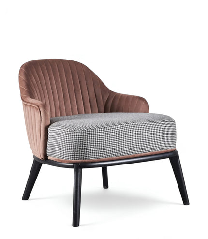 Front angled view of the Vaya Home Carruba accent chair with curved arms, a rose gold channel-tufted back, gray upholstered seat, and black legs.