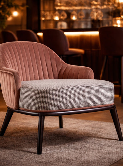 Vaya Home Carruba accent chair with a rose gold channel-tufted back, gray upholstered seat, and black legs, styled in a warm lounge setting.