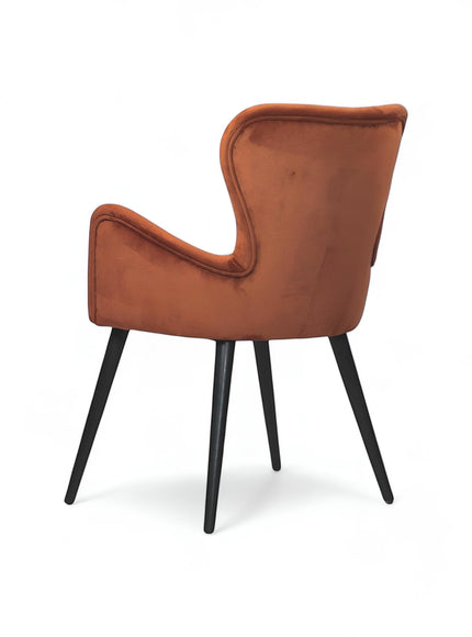 Rear angled view of the Vaya Home Celebrity accent chair with orange upholstery, sculpted arms, and black tapered legs.