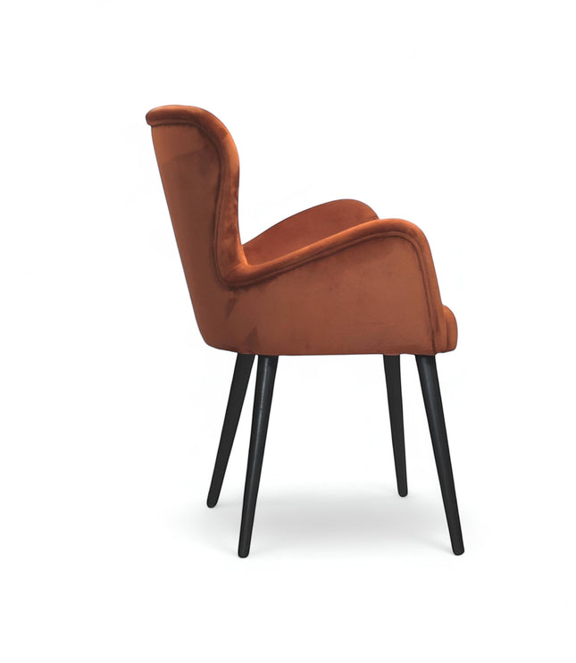 Side view of the Vaya Home Celebrity accent chair with orange upholstery, sculpted arms, and black tapered legs.