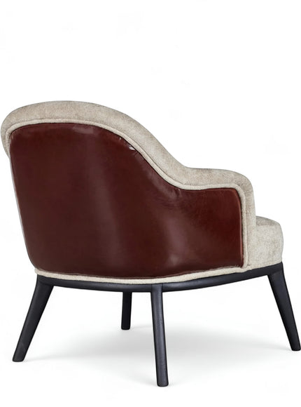 Rear angled view of the Vaya Home Chocolate accent chair with a brown leather outer back, beige upholstered seat, and black legs.