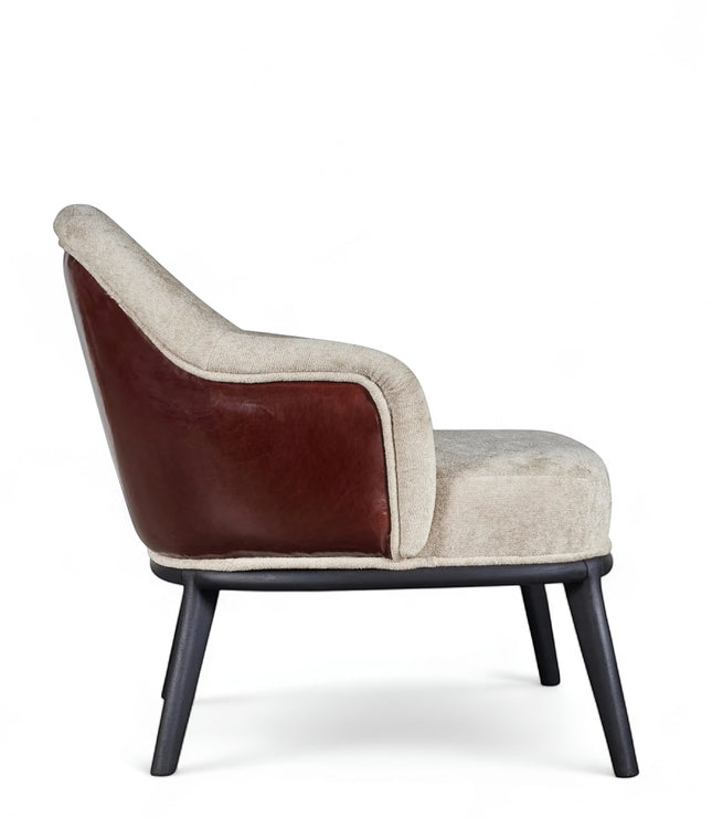 Side view of the Vaya Home Chocolate accent chair featuring beige upholstery, brown leather outer back, curved arms, and black legs.