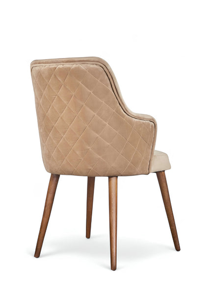 Rear angled view of the Vaya Home Ciervo dining chair featuring beige upholstery, diamond-quilted outer back, and tapered wood legs.