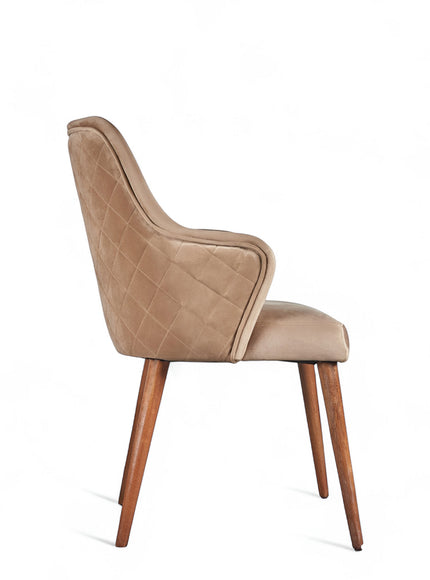 Side view of the Vaya Home Ciervo dining chair with beige upholstery, curved arms, and tapered wood legs.
