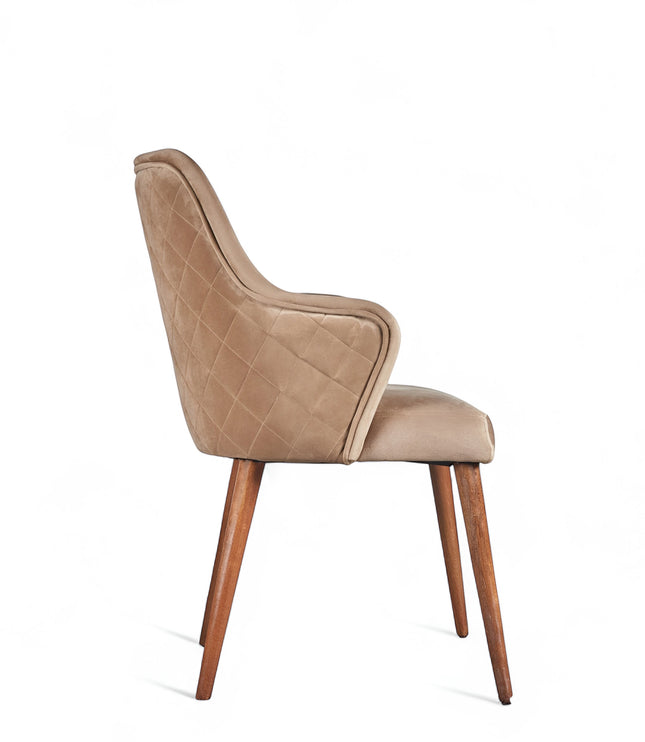 Side view of the Vaya Home Ciervo dining chair with beige upholstery, curved arms, and tapered wood legs.