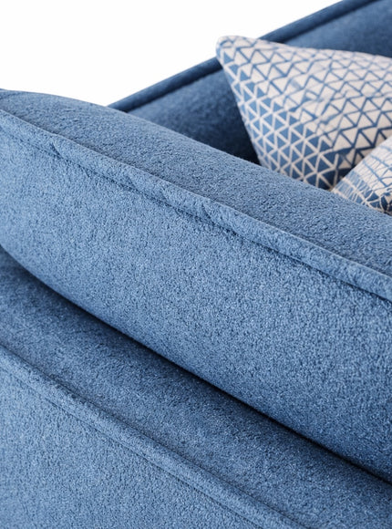 Close-up of the Vaya Home Cobalt sofa showing blue upholstery, layered back cushions, and patterned accent pillow detail.