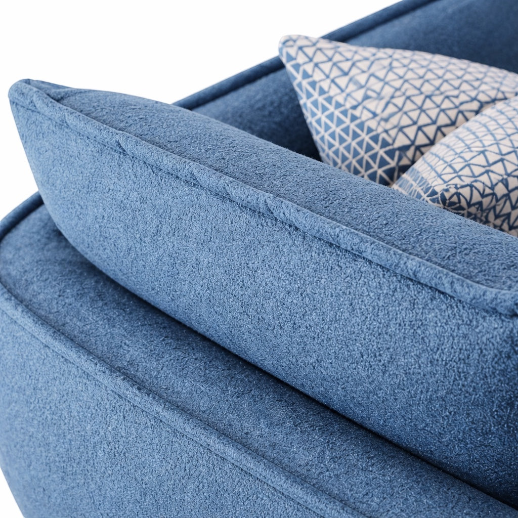Close-up of the Vaya Home Cobalt sofa showing blue upholstery, layered back cushions, and patterned accent pillow detail.