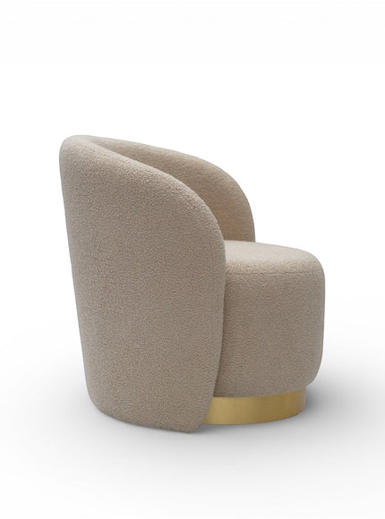 Side angled view of the Vaya Home Cocoon accent chair featuring beige boucle upholstery, a rounded sculptural back, and gold base trim.