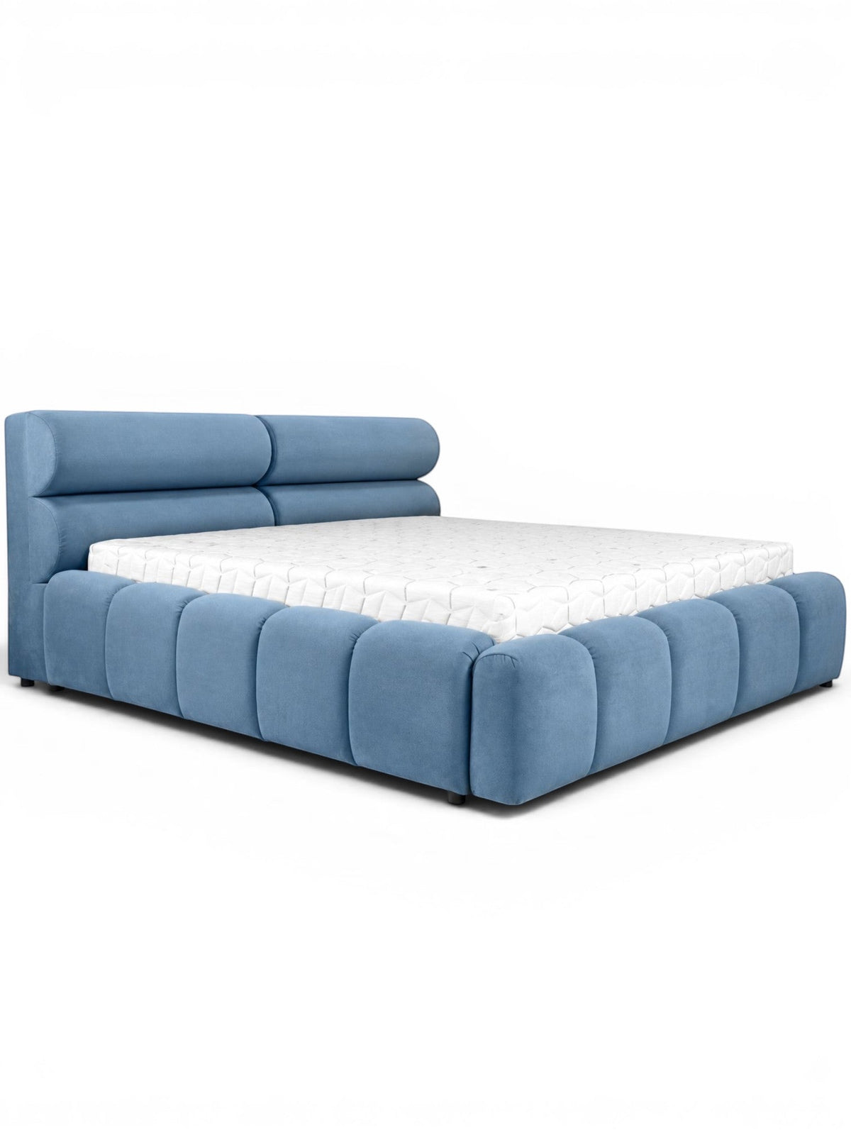Front angled view of the Vaya Home Como bed with blue upholstery, a padded headboard, and a low platform frame with channel detailing.