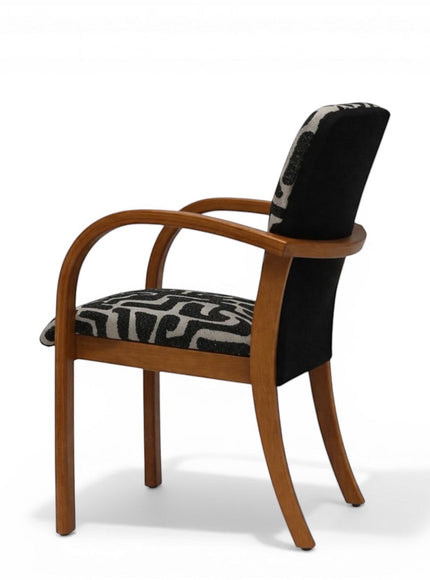 Angled back view of the Vaya Home Contour accent chair with curved wood frame, black rear upholstery panel, and patterned seat.